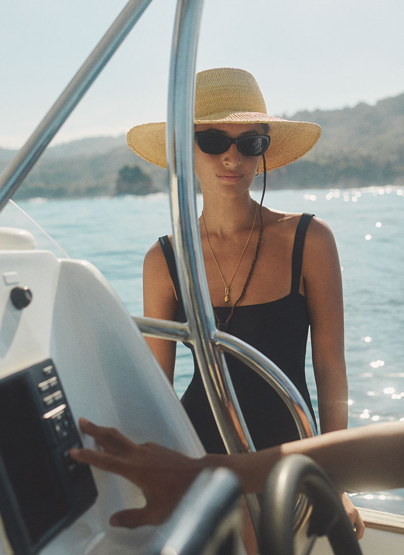 A guest enjoying a scenic boat ride along the coastline near NIHI Sumba, wearing a wide-brimmed hat and sunglasses while taking in the clear blue waters and surrounding natural beauty of the island.
