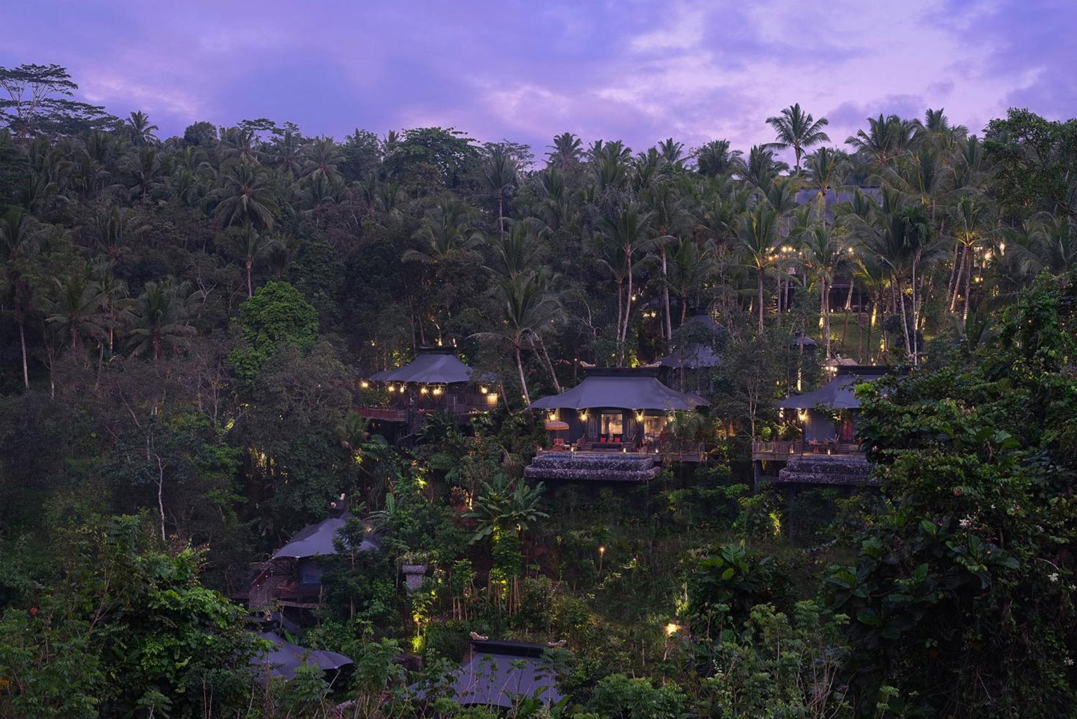 Aerial view of Capella Ubud’s luxury tented villas nestled within the tropical rainforest of Bali at twilight, part of the 'Awaken to Magic' transformative journey with NIHI Sumba.