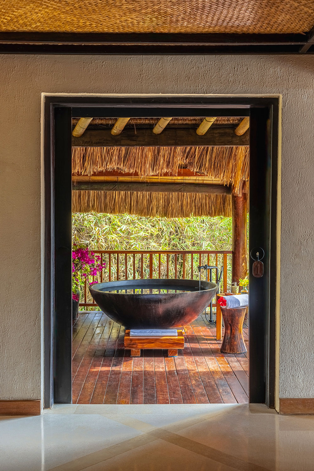 Outdoor bathtub on a private deck at Lulu Amahu Villa, a one-bedroom accommodation at NIHI® Sumba with open-air bathing surrounded by lush tropical foliage.
