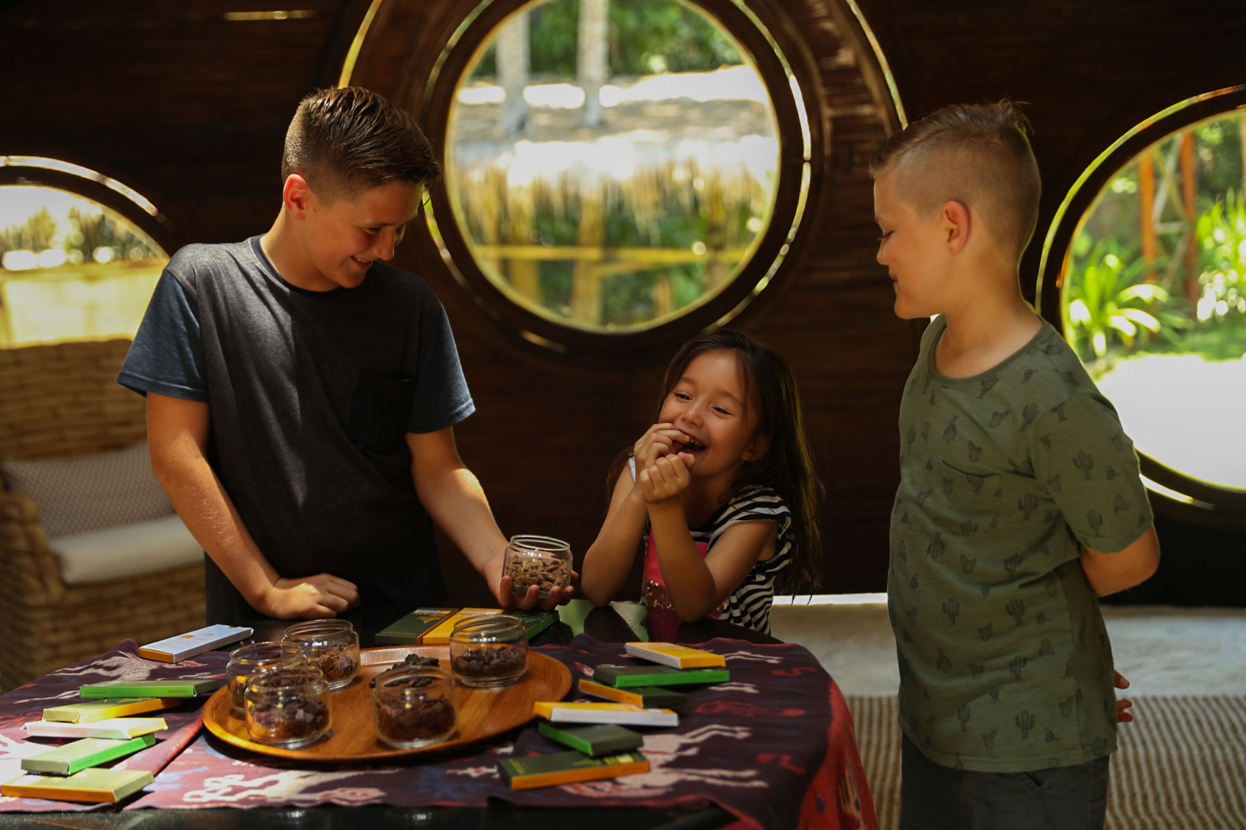 Children sharing a joyful moment while tasting and exploring chocolate samples inside Chris & Charly’s Chocolate Factory at NIHI Sumba.