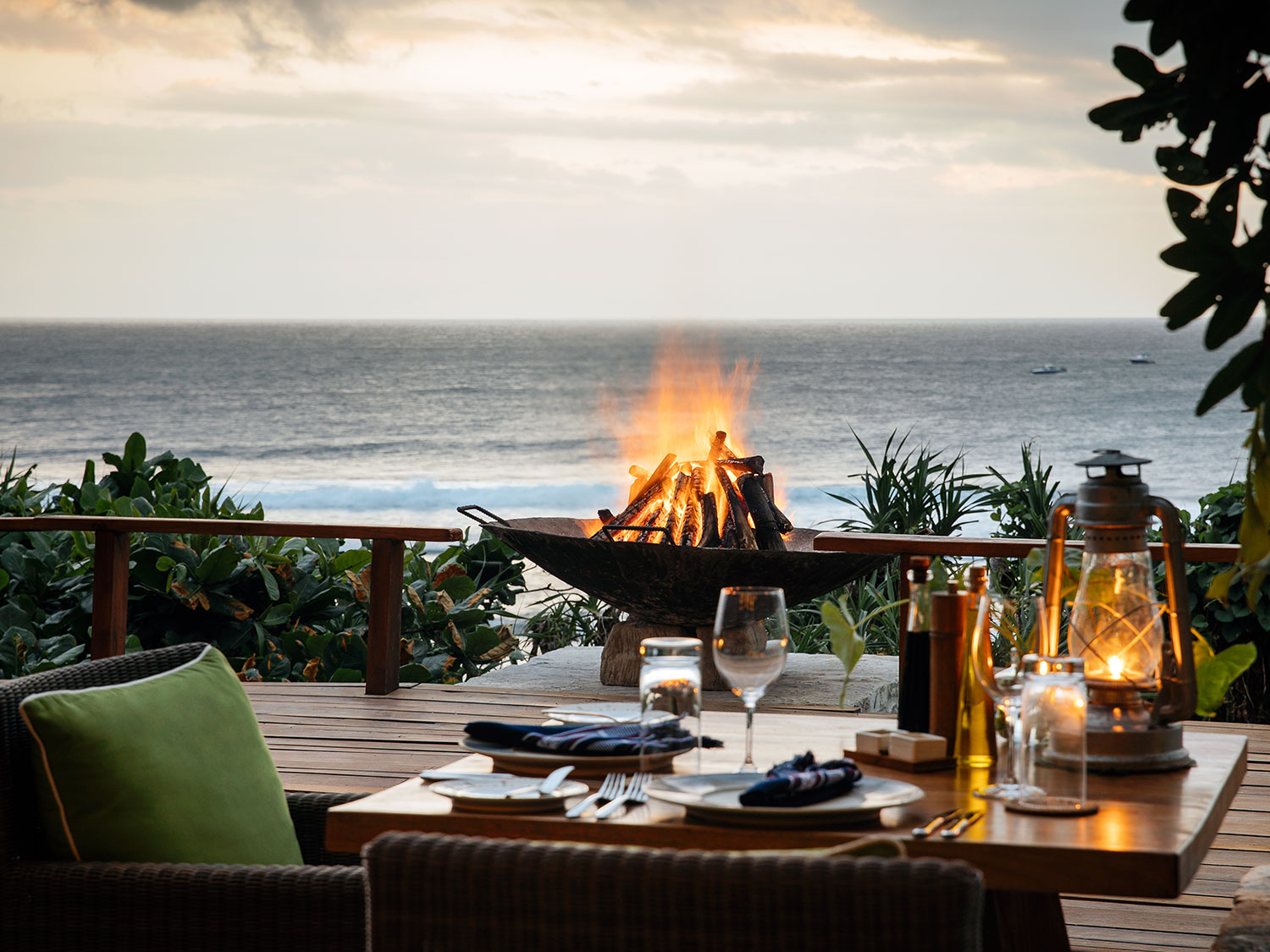 A beautifully set table overlooking the ocean at Ombak Restaurant, featuring a cozy fire pit and lanterns, creating a romantic dining atmosphere. The stunning view of the Indian Ocean complements the relaxed, open-air ambiance of the resort’s main dining venue.