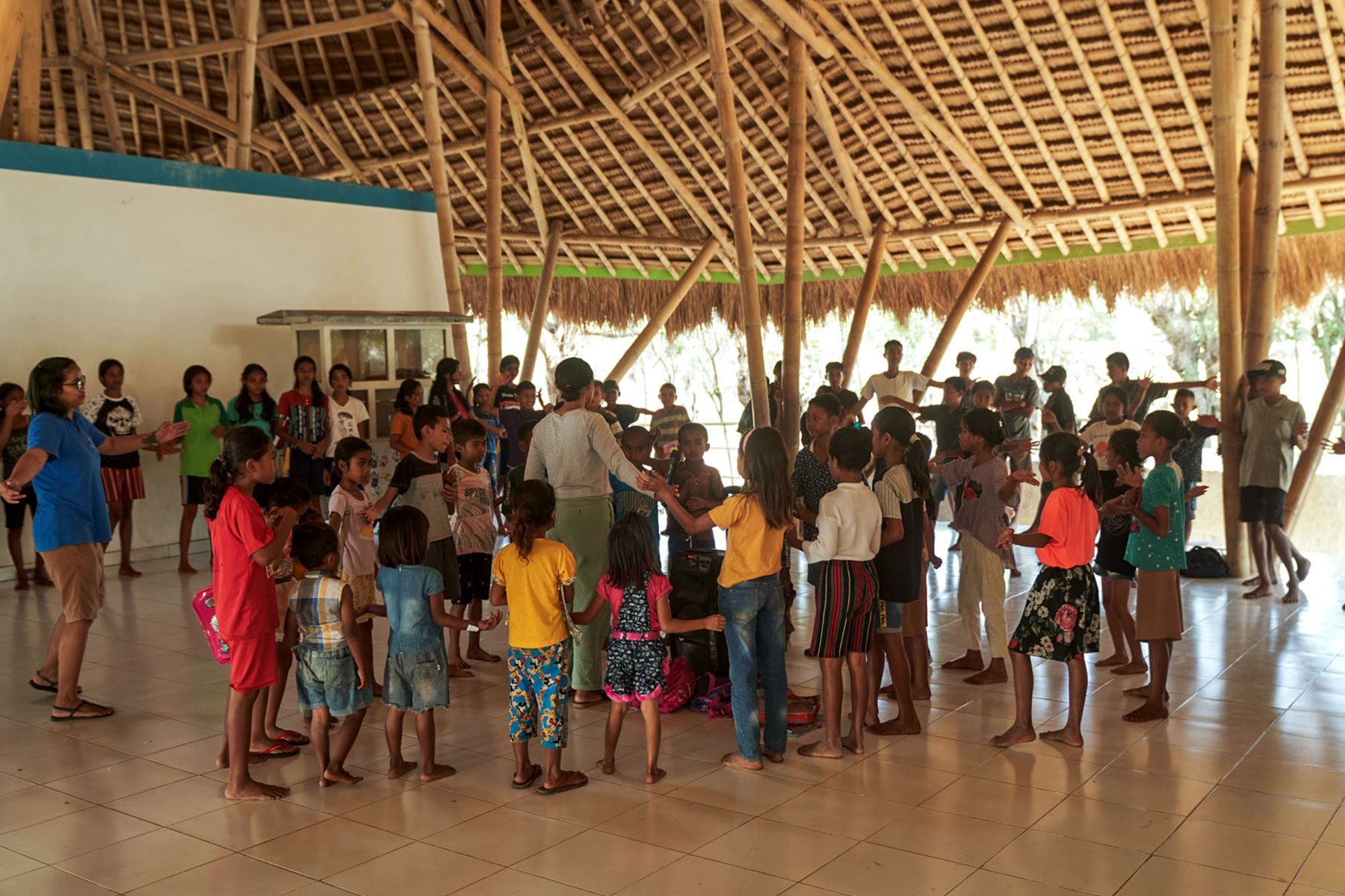 Sumbanese children joyfully participating in an English class activity at the Learning Development Center, supported by NIHI Sumba and the Burch Family Foundation, to enhance language and social skills through songs and interactive learning.