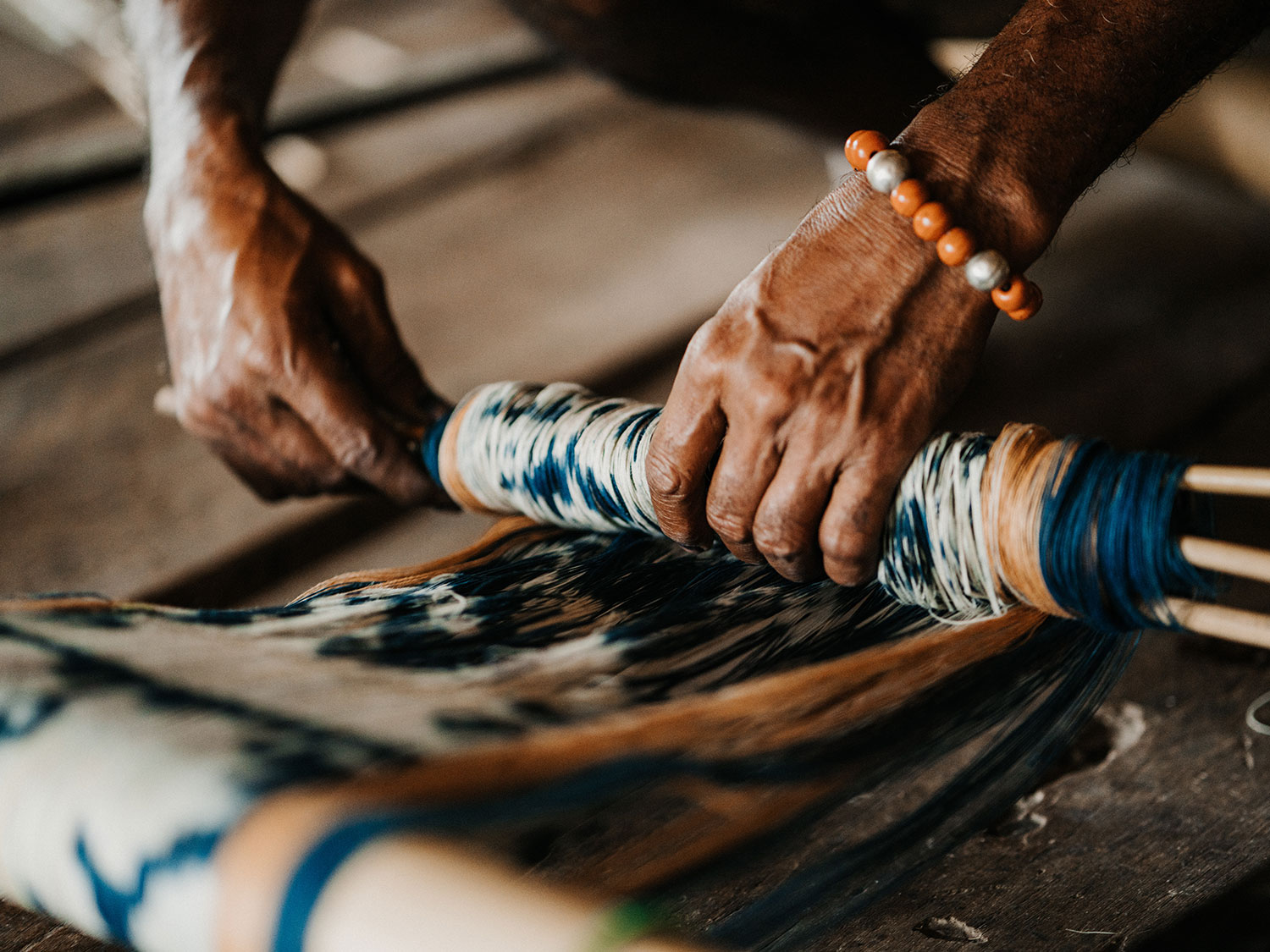 Close-up of a Sumbanese artisan’s hands skillfully preparing dyed threads for traditional ikat weaving at NIHI Sumba.