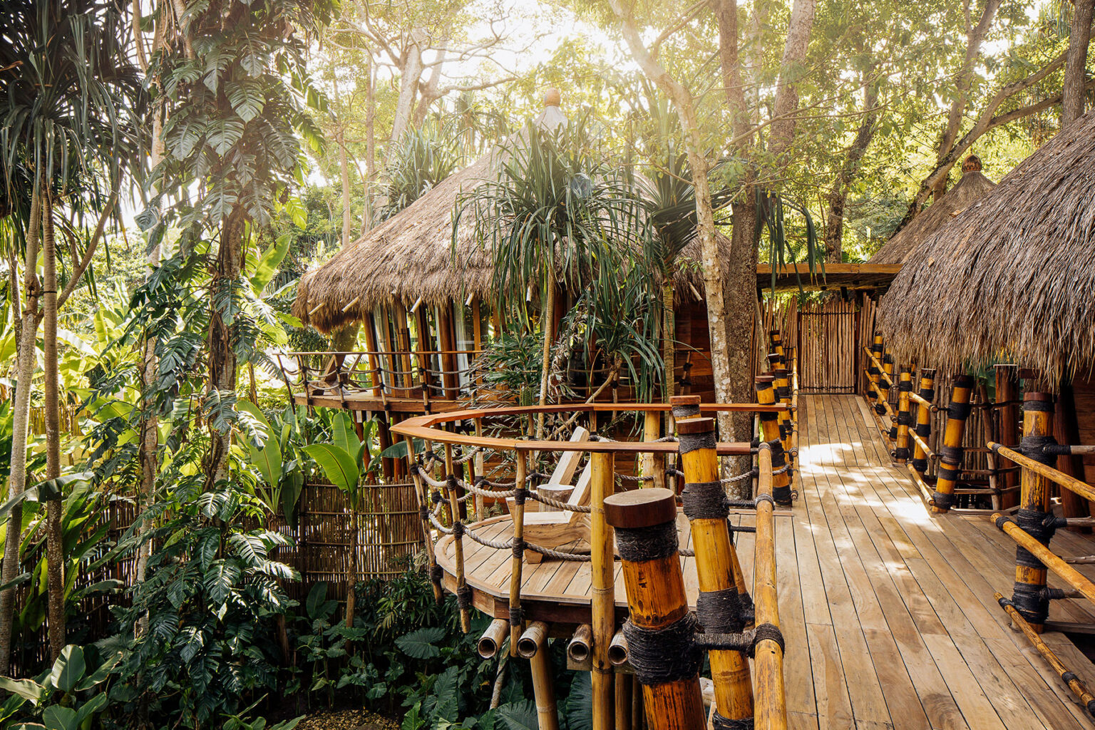 Elevated bamboo walkway connecting the jungle-level thatched suites of Mamole Treehouse Villa, surrounded by dense tropical foliage at NIHI Sumba.
