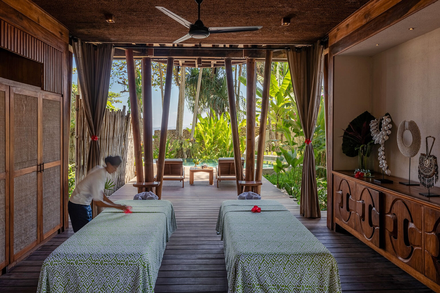 Spacious open-air spa treatment room at Mamole Tree House, featuring twin massage beds, tropical foliage, and a private plunge pool surrounded by natural wood and woven decor at NIHI Sumba.