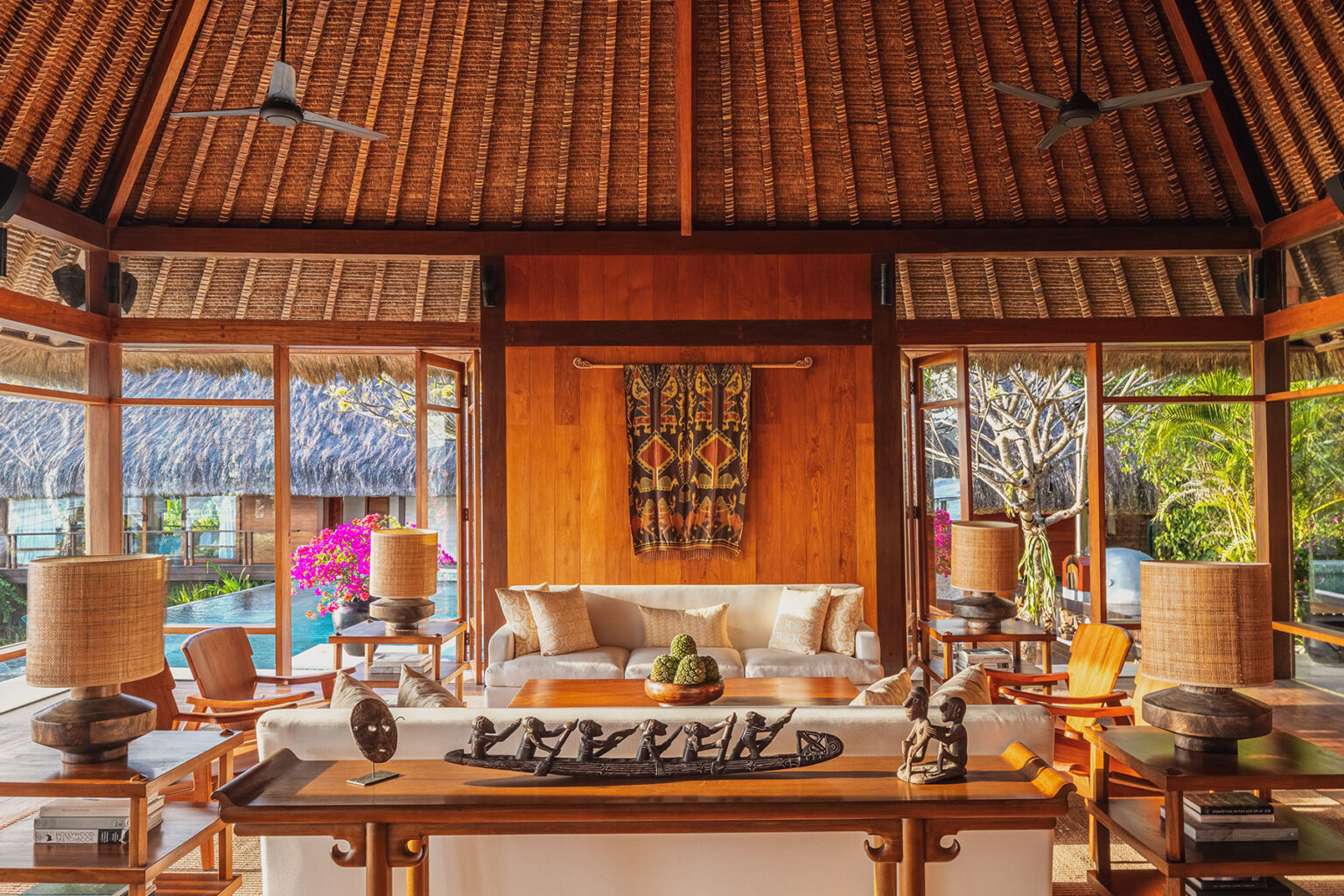 Luxurious open-plan living room at Raja Mandaka Villa in NIHI Sumba, featuring Sumbanese ikat art, traditional woodcrafts, and panoramic views of the private pool and tropical gardens.