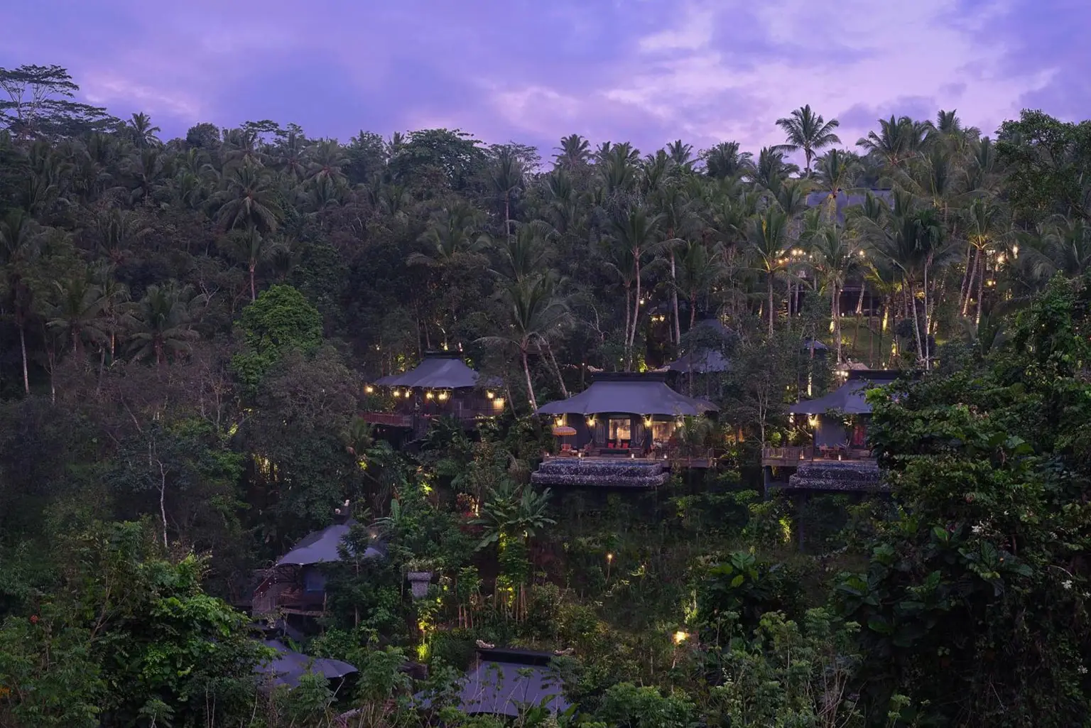 Aerial view of Capella Ubud’s luxury tented villas nestled within the tropical rainforest of Bali at twilight, part of the 'Awaken to Magic' transformative journey with NIHI Sumba.