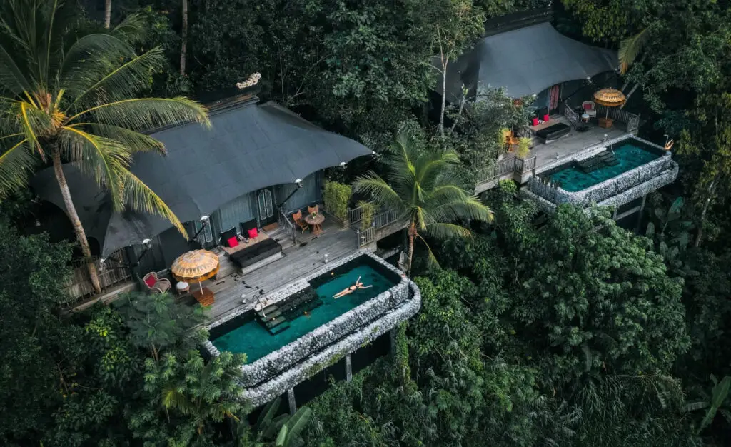 Aerial view of a luxury tented retreat at Capella Ubud, Bali—one of NIHI’s partner properties—featuring a private saltwater pool surrounded by dense rainforest, offering an immersive jungle experience.