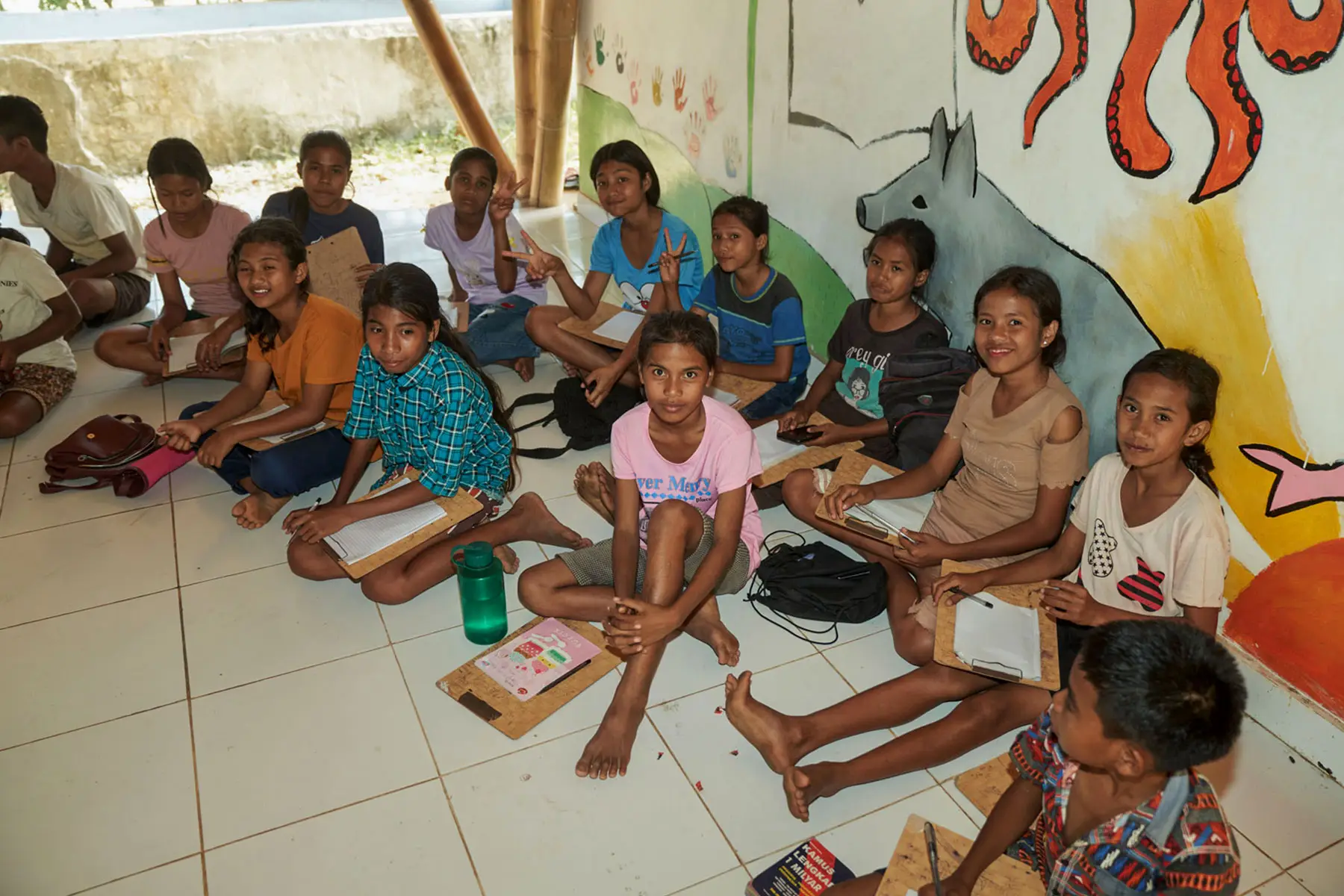 Engaged Sumbanese children reacting with curiosity and amusement during a lively English lesson at the Sumba Foundation’s Learning Development Center.