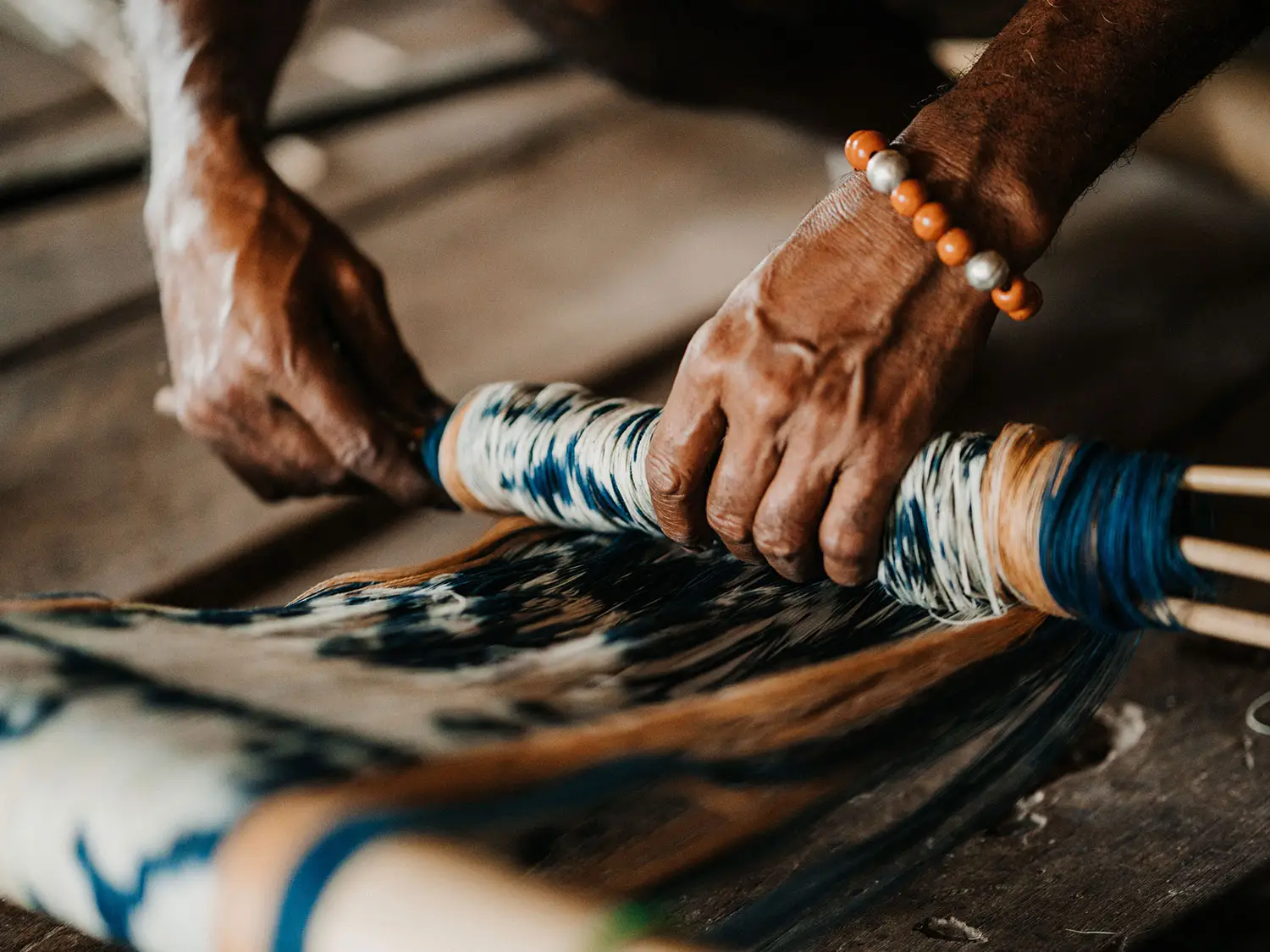 Close-up of a Sumbanese artisan’s hands skillfully preparing dyed threads for traditional ikat weaving at NIHI Sumba.