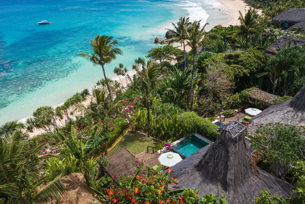 Aerial view of Marangga Occy’s Villa at NIHI Sumba, showcasing the villa’s private plunge pool, outdoor dining area, and lush tropical gardens leading directly to the secluded white-sand Nihiwatu Beach and turquoise sea.
