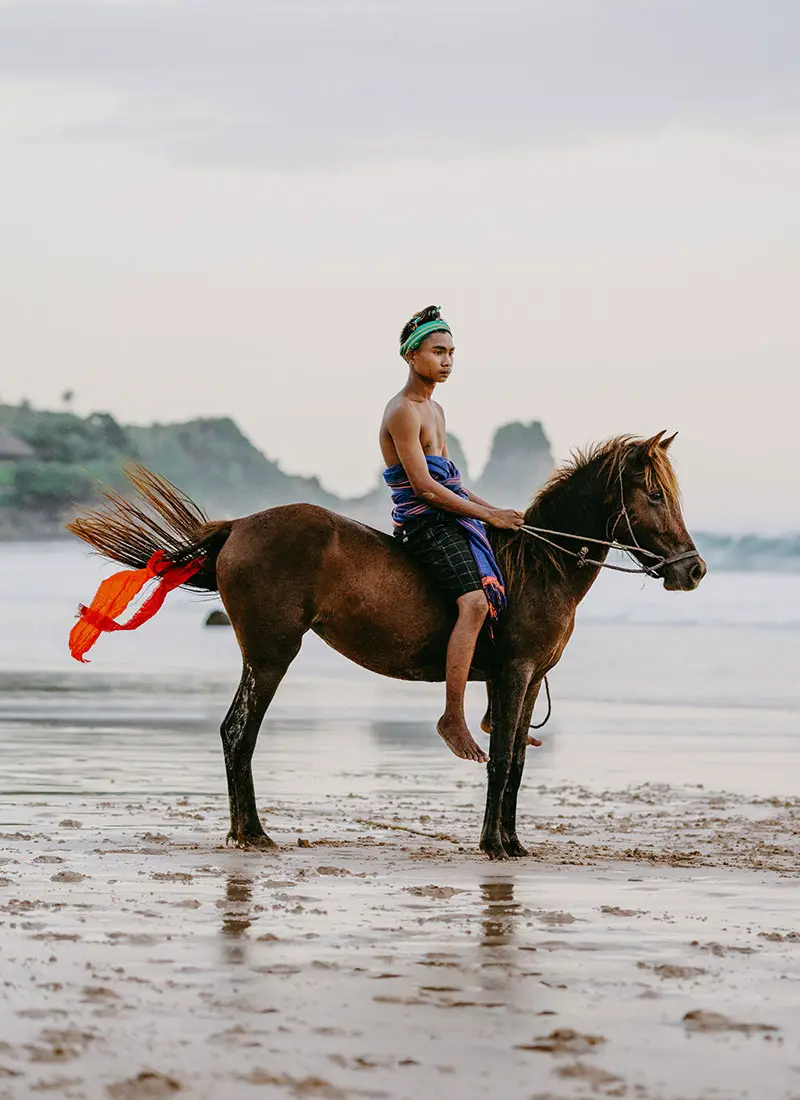 Young Sumbanese horse rider in traditional attire during Pasola demonstration at NIHI Sumba, Indonesia.