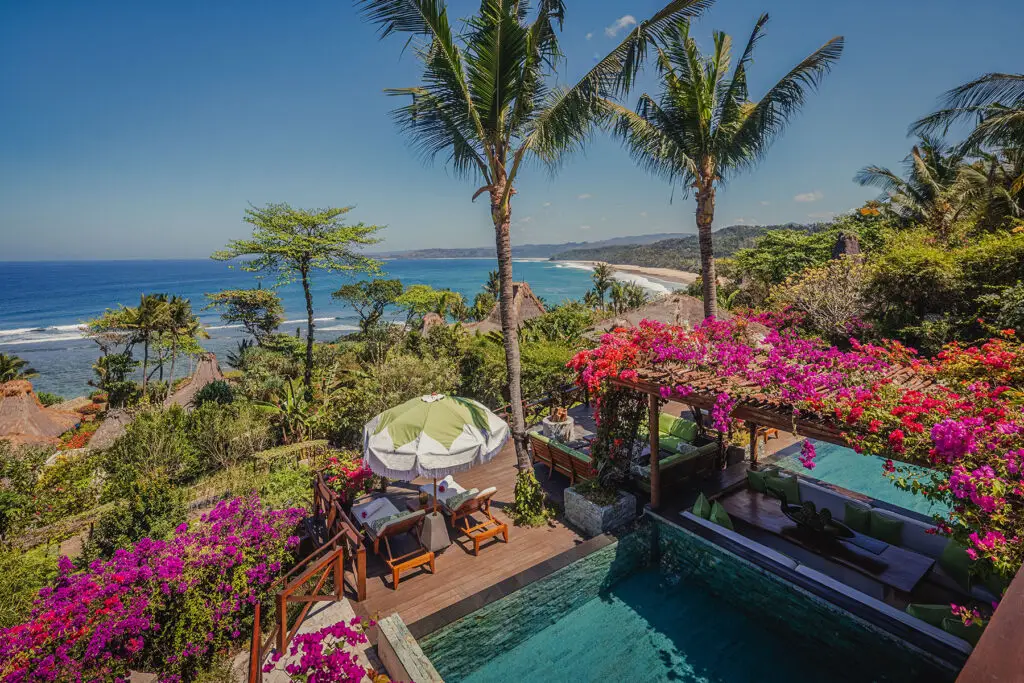 Aerial view of Puncak – Occy’s Left in NIHI Sumba, Indonesia, featuring a private infinity pool, vibrant bougainvillea, palm trees, and breathtaking views of the Indian Ocean coastline