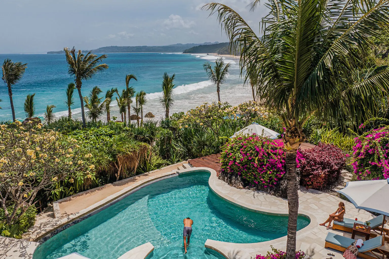 A guest swimming in the private infinity pool with stunning ocean views, surrounded by lush tropical gardens at Putri Wamoro Beach, NIHI Sumba.