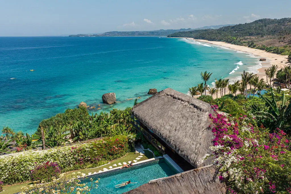 Aerial view of Raja Mandaka, Chris Burch’s private villa at NIHI Sumba, overlooking the turquoise waters of the Indian Ocean and the resort’s 2.5 km stretch of white sand beach, surrounded by lush tropical greenery