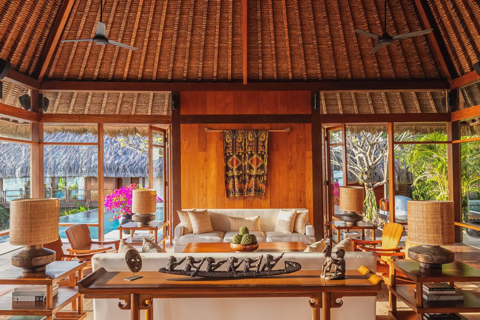 Luxurious open-plan living room at Raja Mandaka Villa in NIHI Sumba, featuring Sumbanese ikat art, traditional woodcrafts, and panoramic views of the private pool and tropical gardens.