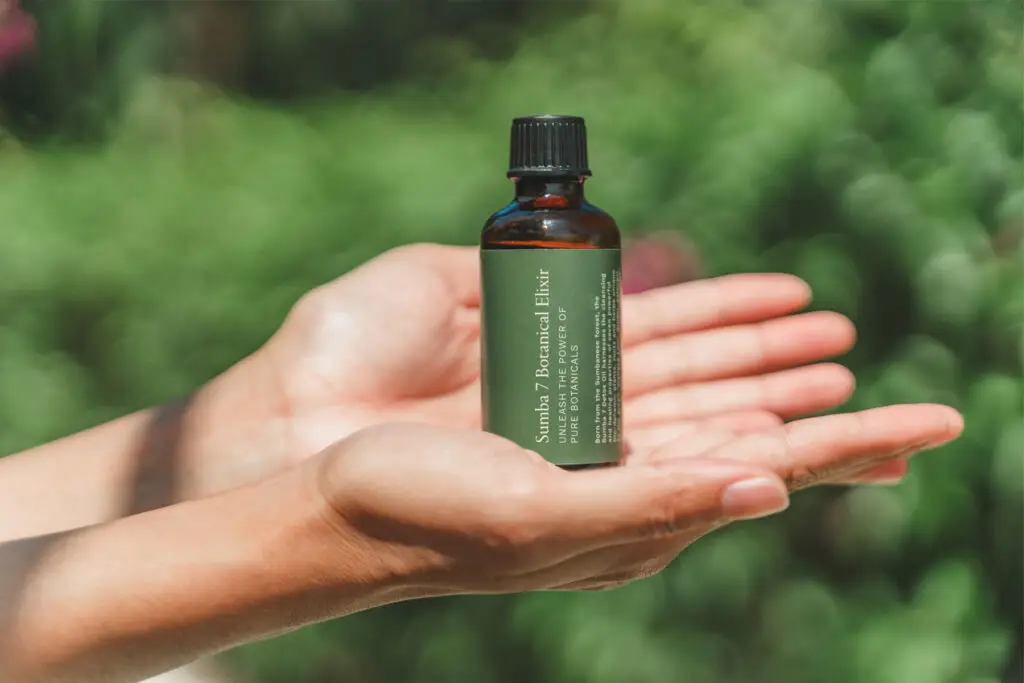Hands gently presenting a bottle of Sumba 7 Botanical Elixir, crafted from seven healing botanicals and rooted in traditional Sumbanese wellness rituals.